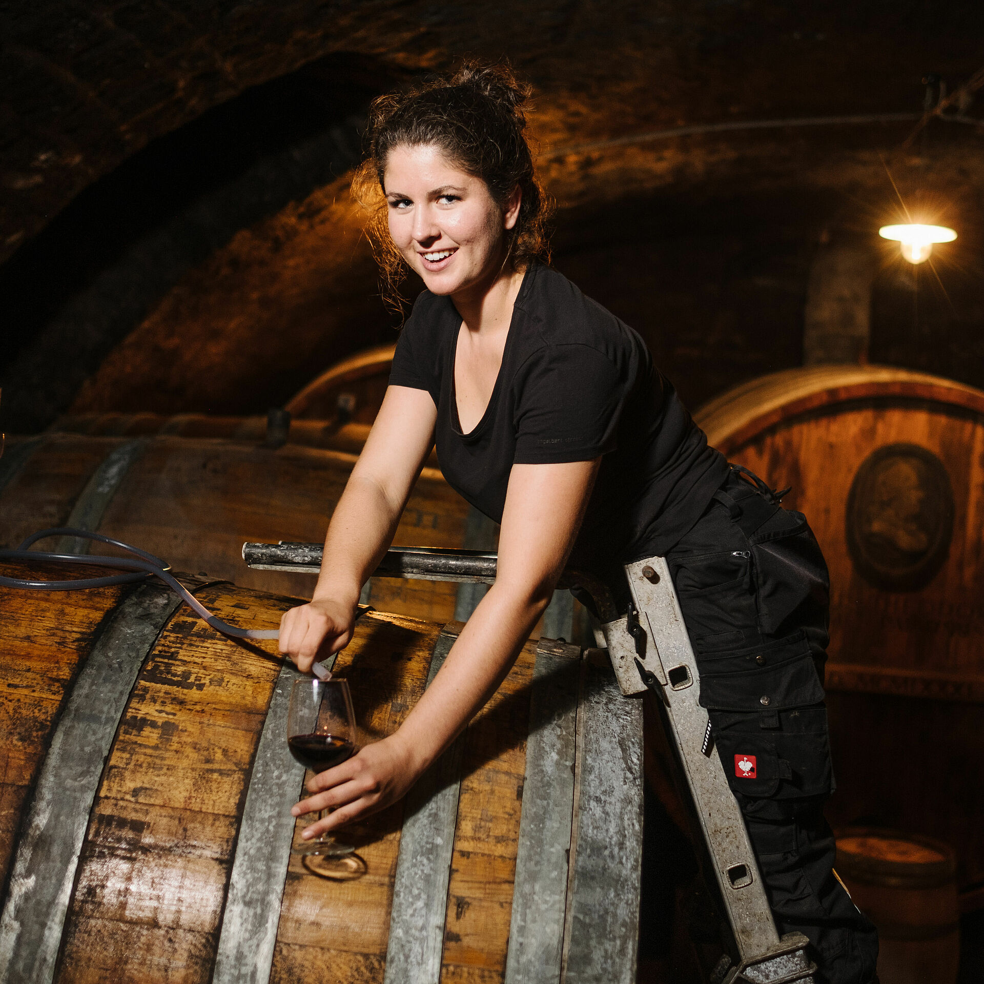 Viticulture student sampling a red wine in the barrique cellar of her partner winery in Neustadt