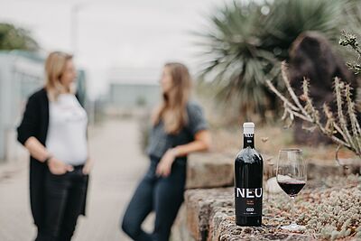 NEO wine in the foreground, a conversation between two people in the background